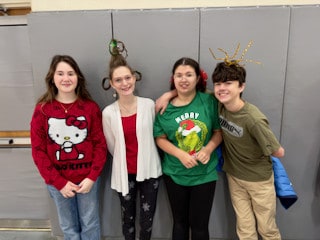 Four Mayflower students posing together in festive clothing