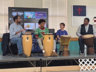 Students performing together on hand drums
